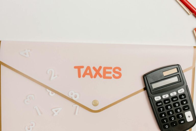 Flat lay of a calculator and folder labeled 'Taxes' for finance and accounting.